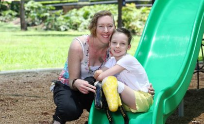 Nine year-old sepsis survivor Mia Wilkinson sitting on slide with mother Amy. Supplied.